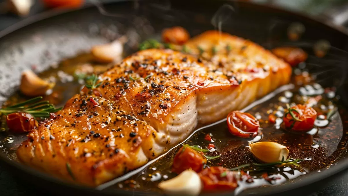 Skrei fillet sizzling in a hot pan with olive oil and garlic.