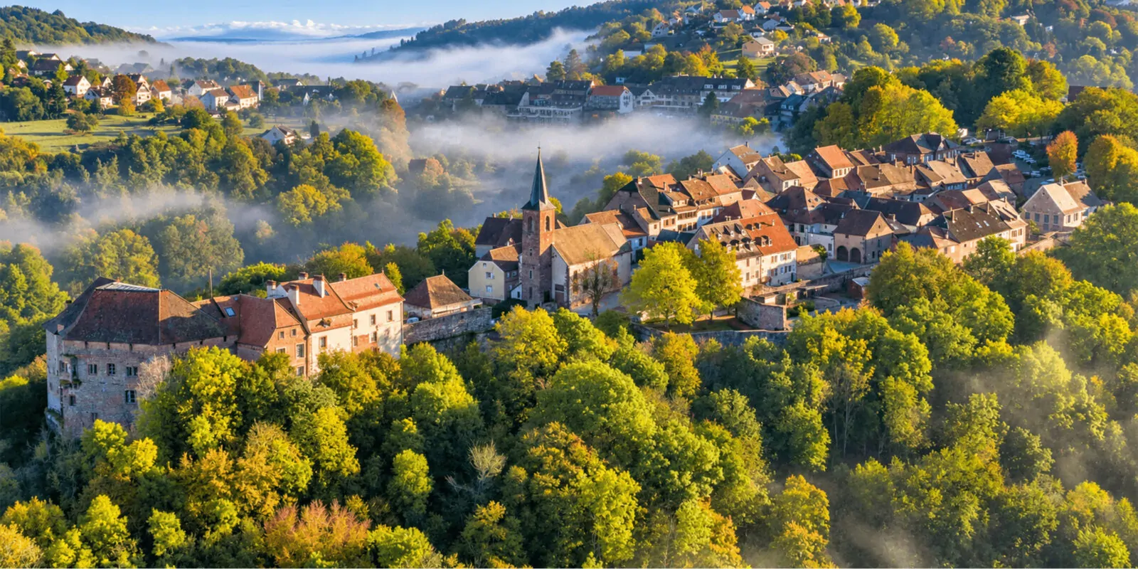 Village perché de La Petite-Pierre et son château sur leur crête de grès, enveloppés de brume au-dessus des forêts